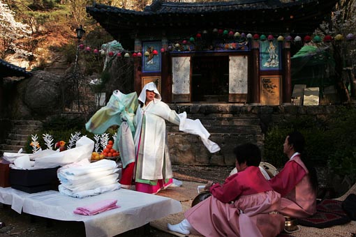 빽빽한 숲을 뚫고 비치는 새벽빛을 받으며 춤을 추는 무당의 모습은 서럽기도, 아름답기도 하다 